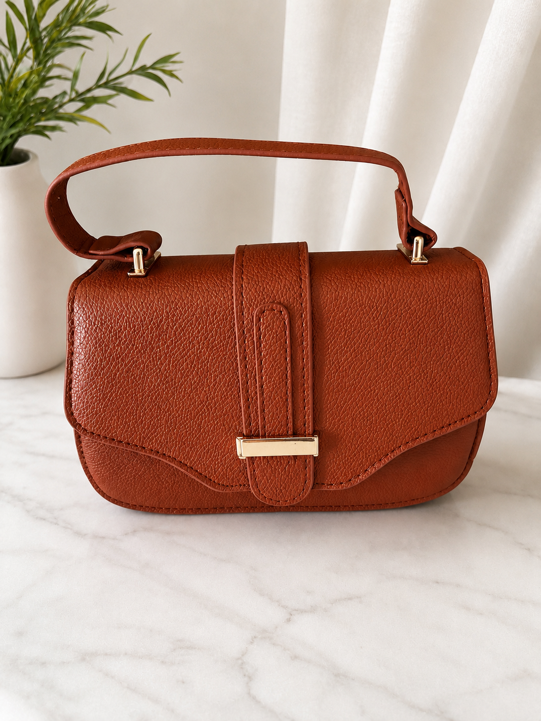 Elegant brown textured top handle crossbody handbag with gold hardware for women.
